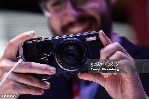An attendee takes a photograph with a Hasselblad True Zoom Moto Mod modular camera mounted on a Motorola Moto Z smartphone at the Lenovo Group Ltd....