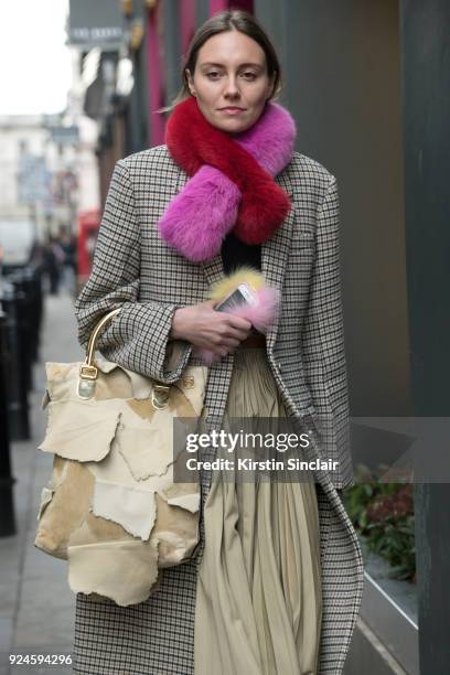 Stylist Tess Yopp wears a Shrimps scarf and phone case, Stella McCartney coat, Loewe bag and skirt on day 5 of London Womens Fashion Week...