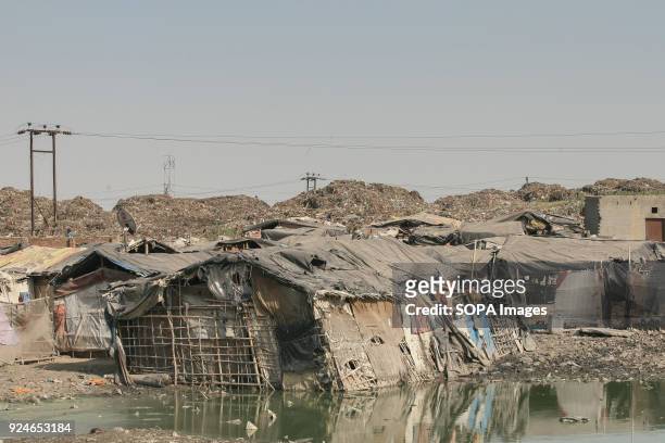 Houses of slum seen built right next to dirty rubbish water. Over 25 million people live in Delhi, India. What is particularly problematic in India...