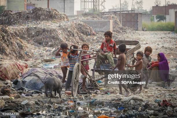 Group of children from the slum seen paying on a pile of rubbish. Over 25 million people live in Delhi, India. What is particularly problematic in...