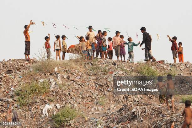 Group of children from the slum seen spending their afternoon playing on a pile of rubbish. Over 25 million people live in Delhi, India. What is...