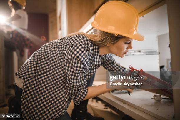 female manual worker using caulk gun while working on home improvement. - caulk stock pictures, royalty-free photos & images