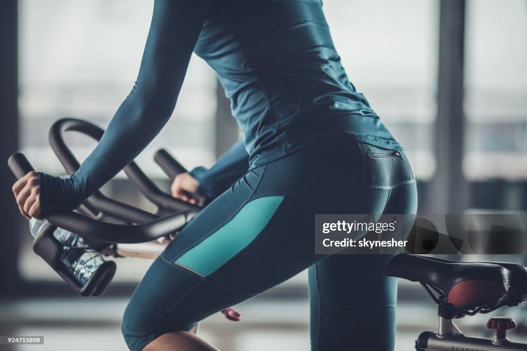 Irreconocible mujer atlética hacer ejercicio en bicicleta estática en un gimnasio.