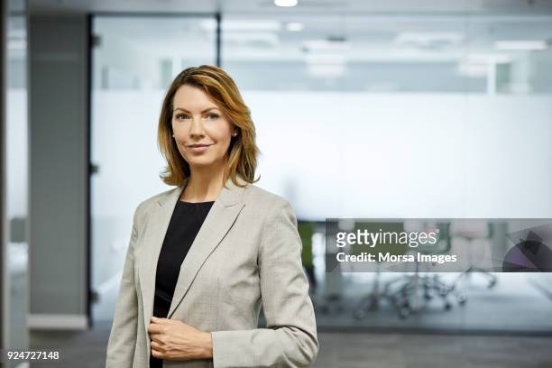 mature businesswoman standing against board room - businesswear stock pictures, royalty-free photos & images