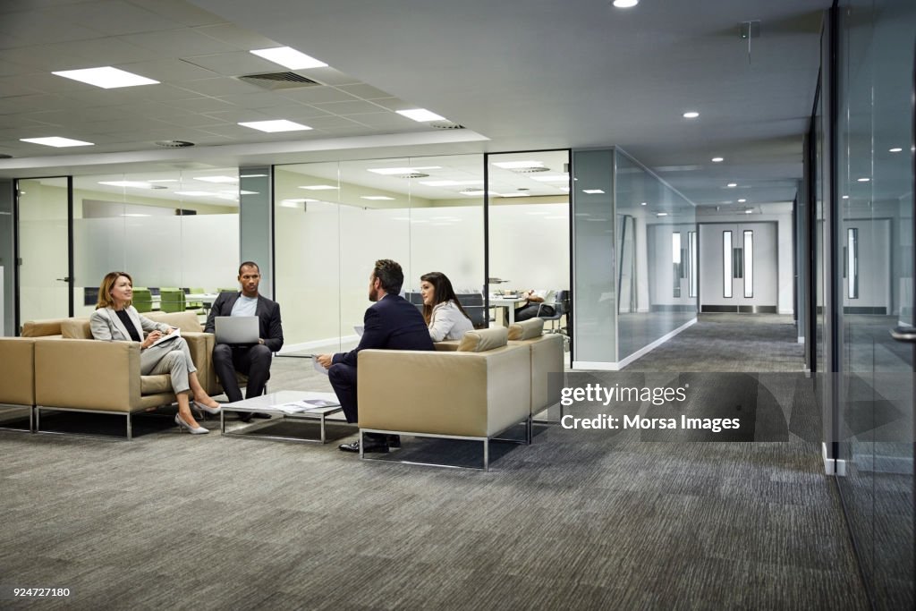 Colleagues discussing strategy in lobby at office