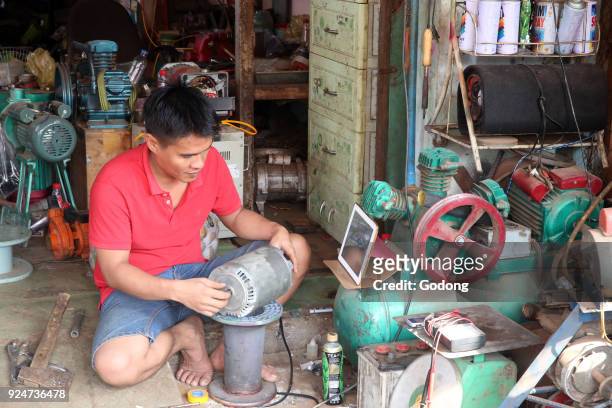 Mechanic working on a compressor in his shop. Thay Ninh. Vietnam. .