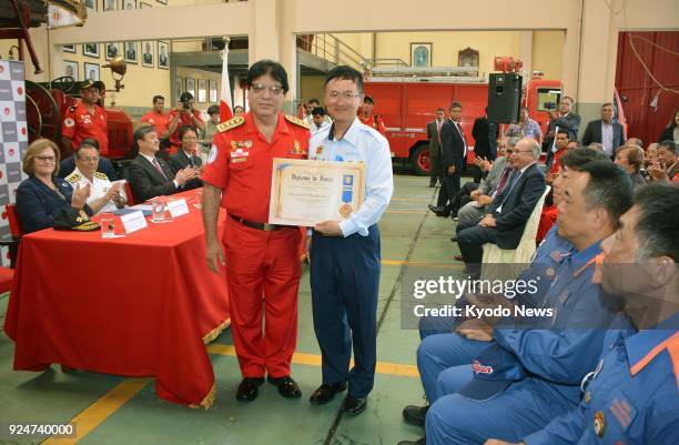 International Division Director of the Japan Firefighters Association Akimitsu Furumoto holds a certificate of commendation presented by Peru's...