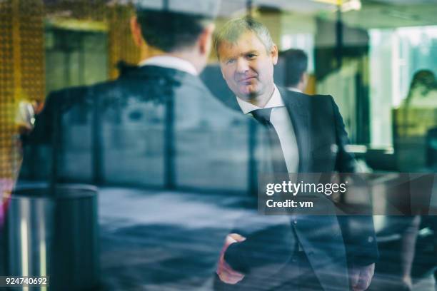 businessmen shaking hands in an office lobby - hedge fund stock pictures, royalty-free photos & images