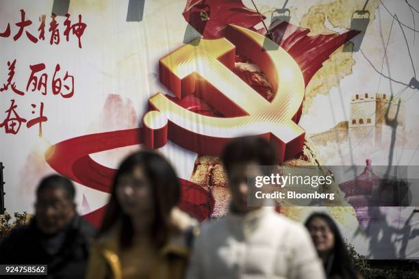 Banner featuring the hammer-and-sickle emblem is displayed on a wall as pedestrians cross a road in Shanghai, China, on Monday, Feb. 26, 2018. Xi...