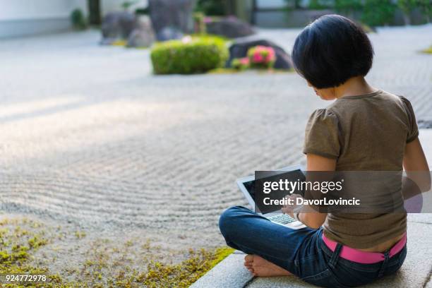 kant, terug kijk op vrouw zitten op het podium van de tempel, typen op een laptop terwijl u geniet van zen tuin van chion-ji tempel in kyoto, japan - chion in stockfoto's en -beelden