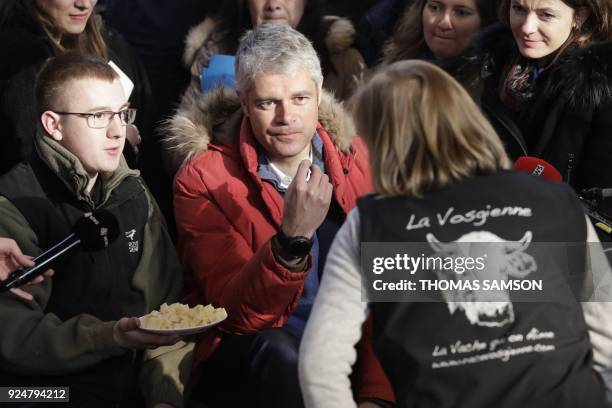 Head of France's rightwing Republicans opposition party Laurent Wauquiez eats cheese as he speaks with a breeder during his visit at the 55th...