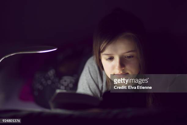 teenage girl reading book at bedtime using night light - bedtime story book stock pictures, royalty-free photos & images