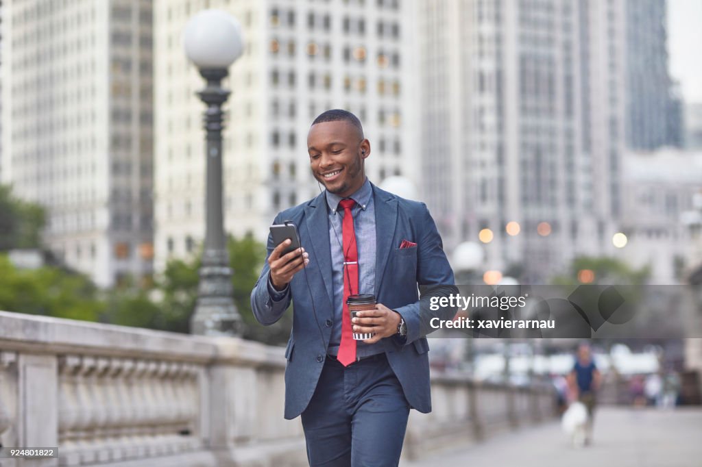 Executive with mobile phone and coffee cup in city