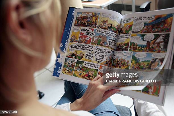 Person poses reading Asterix last comic book by late writer Rene Goscinny and illustrator Albert Uderzo "L'anniversaire d'Astérix et Obélix, le livre...