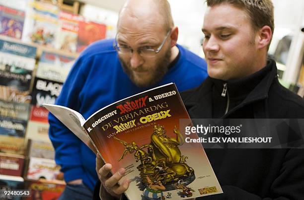 Two men read the anniversary edition of Asterix and Obelix written by late Rene Goscinny, entitled 'De Verjaardag of Asterix and Obelix, the Golden...