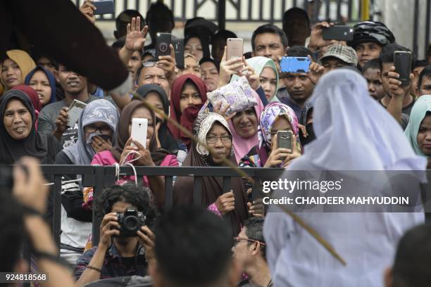 People watch as Tjia Nyuk Hwa an Indonesian Christian, is publicly flogged outside a mosque in Banda Aceh on February 27 for playing a children's...