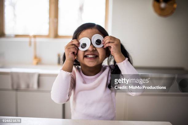 young girl playing with silly googly eyes at home - day 4 stock-fotos und bilder