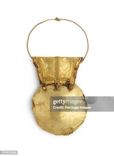 Gold bulla, 1-79. Circular; two very thin gold plates over a ceramic? core; the gold plates are attached by rivets to a trapezoidal loop decorated...