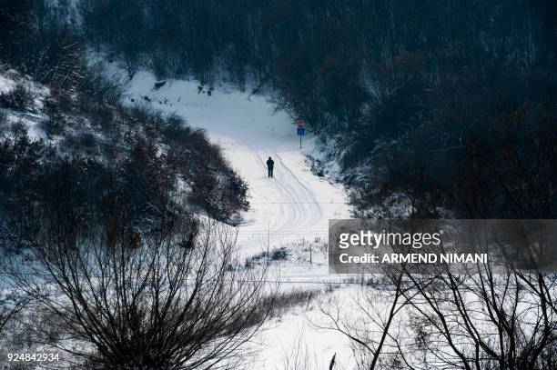 Man walks through on a snow-covered road near the village of Mramor, near Pristina, on February 27, 2018. - Dubbed "The Beast from the East," Europe...