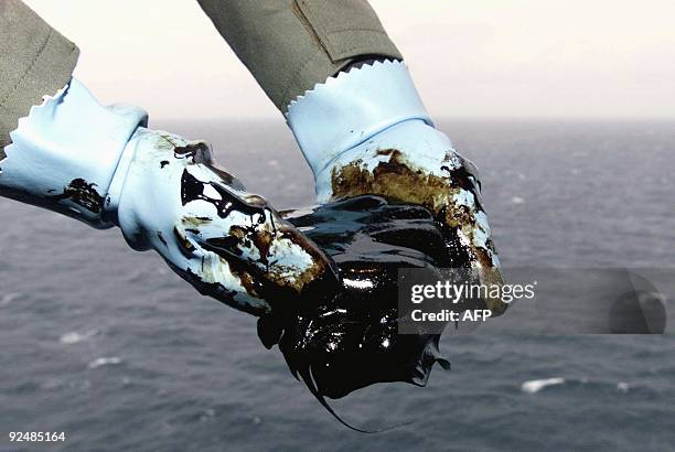 French marine aboard an helicopter holds a viscous sample taken from the oil slick threatening France's Atlantic seabord 17 December 1999. The oil...