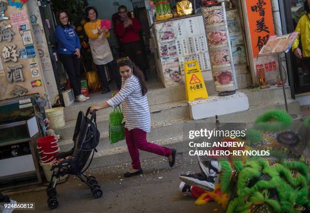 Woman pushes a baby as a man performs a lion dance, following Lunar New Year celebrations, at a restaurant in Yung Shue Wan on Lamma island in Hong...