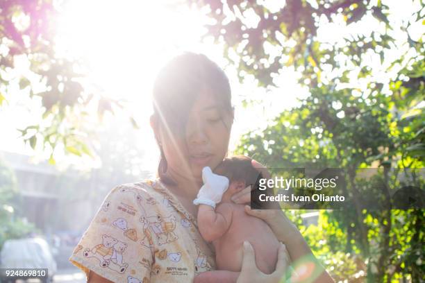 asian woman carrying her baby under sunlight - hot filipina women stockfoto's en -beelden