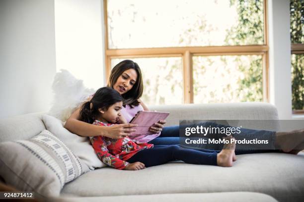 mother and daughter using tablet at home - indian couple at home stock-fotos und bilder