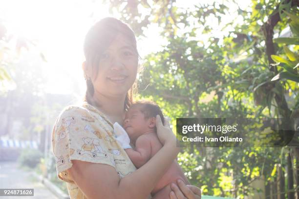 asian woman carrying her baby under sunlight - hot filipina women stockfoto's en -beelden