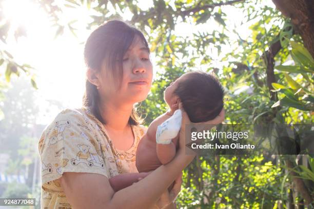 asian woman carrying her baby under sunlight - hot filipina women stock pictures, royalty-free photos & images