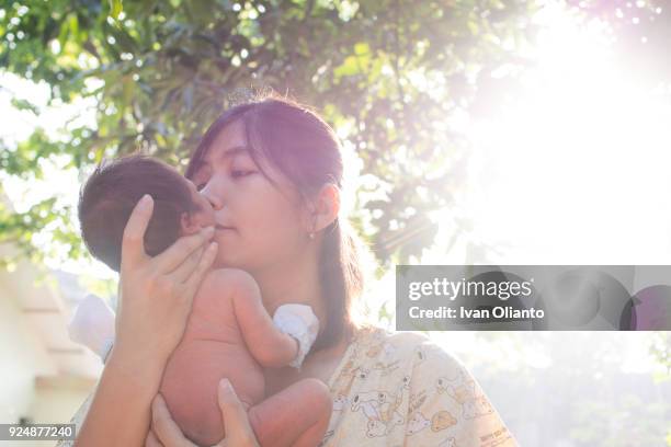 asian woman carrying her baby under sunlight - hot filipina women stockfoto's en -beelden