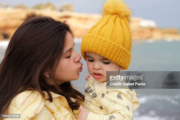 teenager kissing baby boy - costa_del_azahar stock pictures, royalty-free photos & images