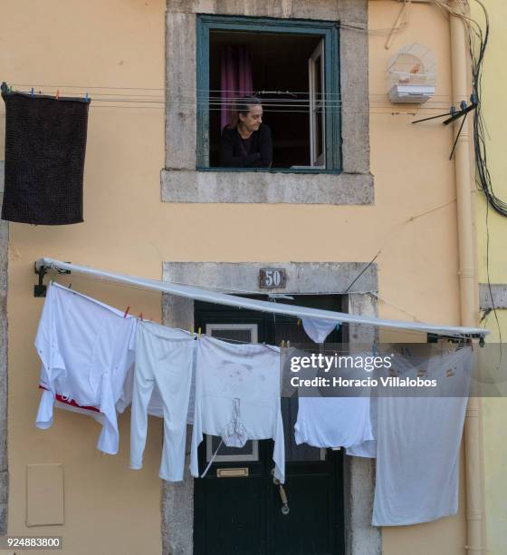 Woman seen at a window above clotheslines in Mouraria neighborhood on February 24, 2018 in Lisbon, Portugal. Mouraria is one of the city's oldest...