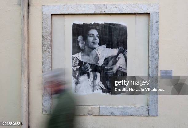 Man walks by a picture of Fado singer Amalia Rodrigues, part of "Retratos de Fado" exhibit, hanging in Mouraria neighborhood on February 24, 2018 in...