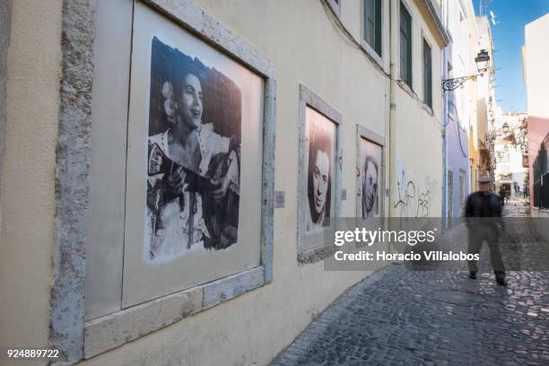 Man walks by portraits of Fado singers Amalia Rodrigues, Fernanda Maria and Francisco Martinho, part of "Retratos de Fado" exhibit, hanging in...