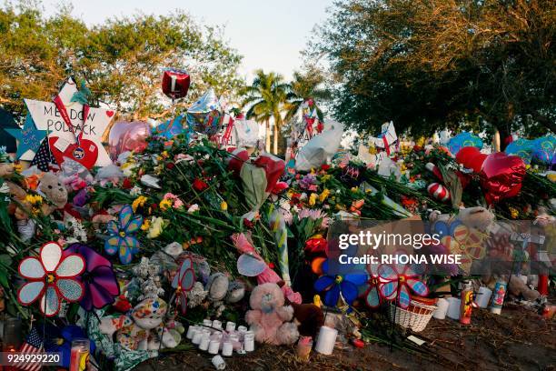 Flowers, candles and mementos sit outside one of the makeshift memorials at Marjory Stoneman Douglas High School in Parkland, Florida on February 27,...