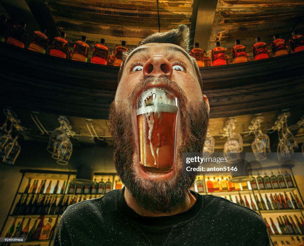 Glass of beer in man's mouth at bar