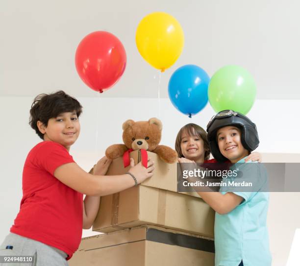 happy brothers playing with balloons and carton box - happy arab family on travel stockfoto's en -beelden