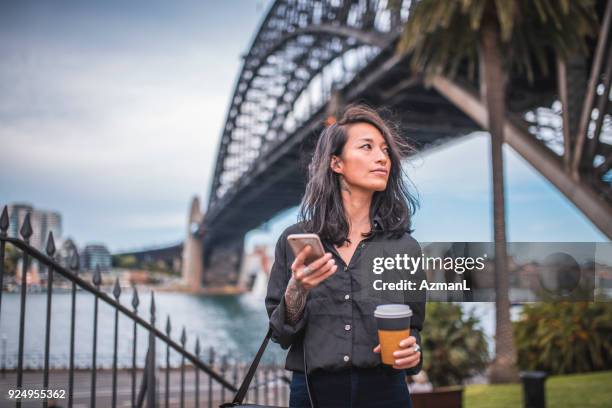 mujer asiática con teléfono en sydney - puente del puerto de sidney fotografías e imágenes de stock