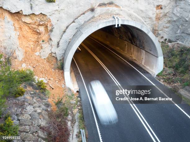 driving a car at high speed  in the entry or exit of a tunnel of an illuminated tunnel. spain - underpass stock pictures, royalty-free photos & images