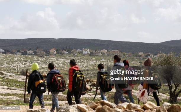 Picture taken on February 27, 2018 shows Palestinian school children walkin gwith their bags through their make-shift village near the Israeli...