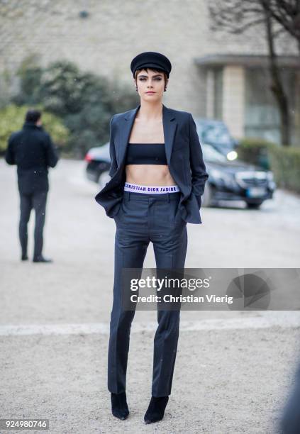 Model Cara Delevingne wearing a cropped top, navy pants, military hat is seen outside Dior on February 27, 2018 in Paris, France.