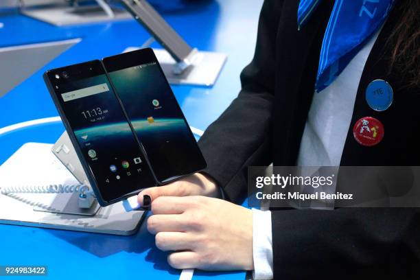 Hostess demonstrates the foldable dual-screened ZTE Axon M smartphone during the Mobile World Congress , the world's biggest mobile fair, on February...