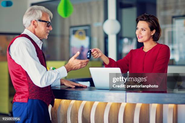 business woman at the office desk is giving car keys to a customer - saleswoman stock pictures, royalty-free photos & images