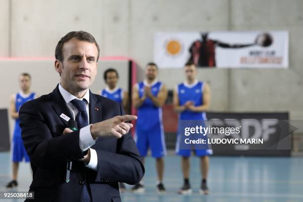 French President Emmanuel Macron watches a display of basketball skills during a visit at the Jesse Owens gymnasium in Villetaneuse near...