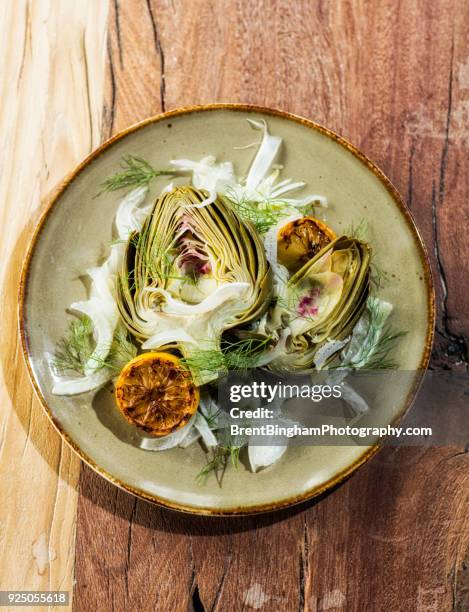 plate on wooden table with halved artichokes, fennel and grilled lemon - farm to table stock pictures, royalty-free photos & images