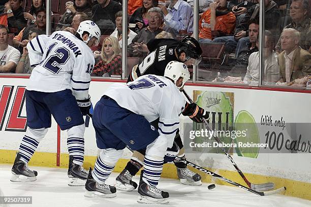 Ian White and Lee Stempniak of the Toronto Maple Leafs fight for the puck alongside the boards against Bobby Ryan of the Anaheim Ducks during the...