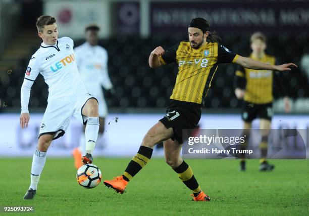 Tom Carroll of Swansea City is tackled by George Boyd of Sheffield Wednesday during the Emirates FA Cup Fifth Round Replay match between Swansea City...