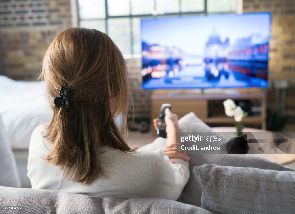 Femme à regarder la télévision à la maison