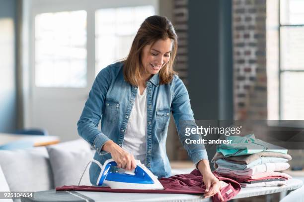 happy woman ironing her clothes at home - presse stock pictures, royalty-free photos & images
