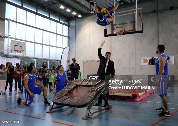 French President Emmanuel Macron gestures as he takes part in display of basketball skills during a visit at the Jesse Owens gymnasium in...